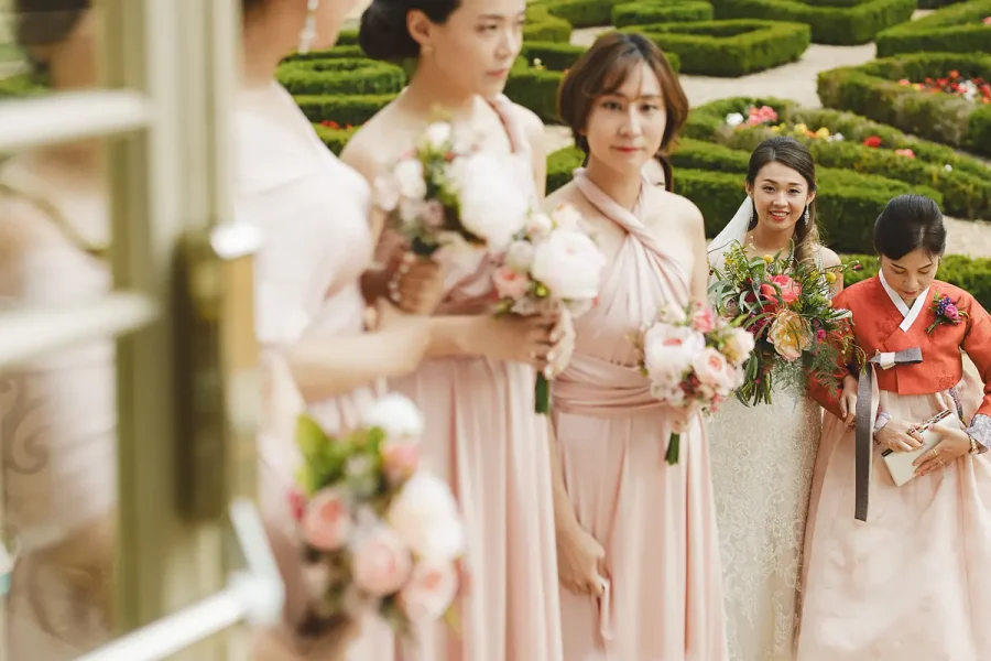 Bride and bridesmaids in blush dresses holding bouquets, with the Highcliffe Castle parterre garden visible behind
