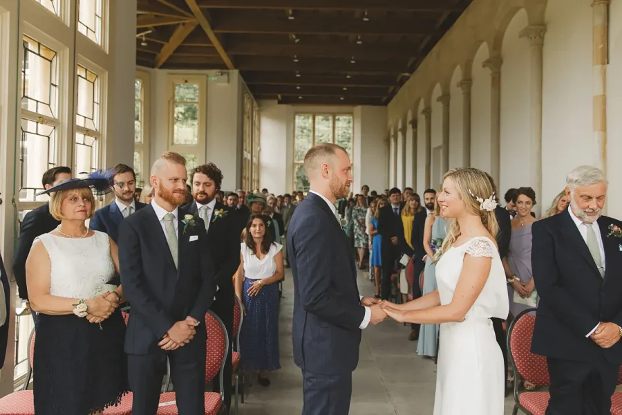 Bride and her father walking to the altar in the Wintergarden at Highcliffe Castle as the groom waits