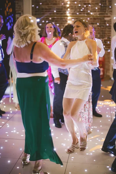 Bride in her short reception dress dancing on the light-up dance floor in the Great Hall at Highcliffe Castle