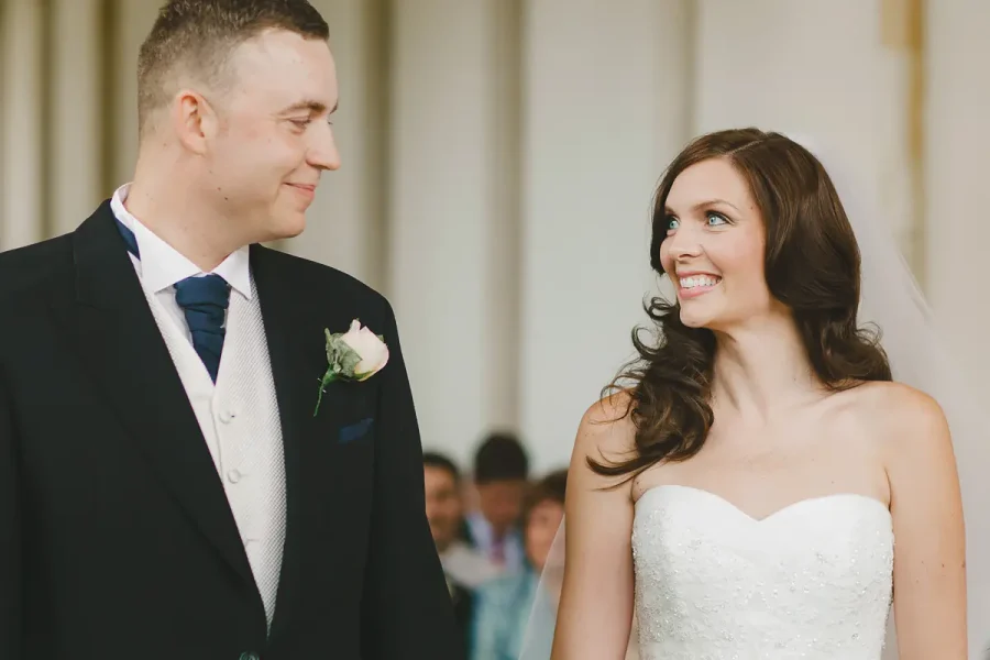 Bride and groom smiling at each other during their ceremony in the Wintergarden at Highcliffe Castle