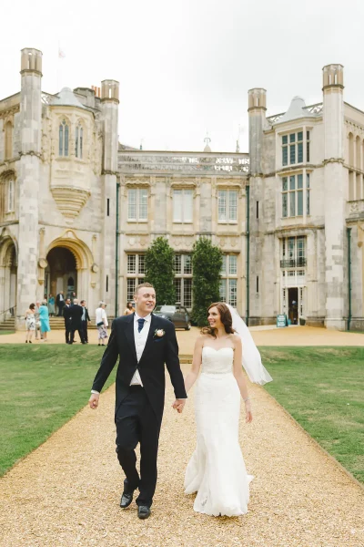 Bride and groom walking hand in hand along the path in front of Highcliffe Castle after their ceremony