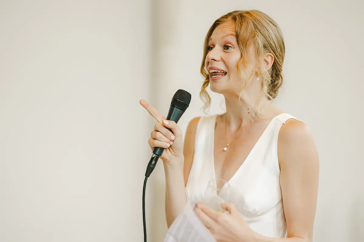 Bride delivering her speech with a gesture and microphone in the Wintergarden at Highcliffe Castle