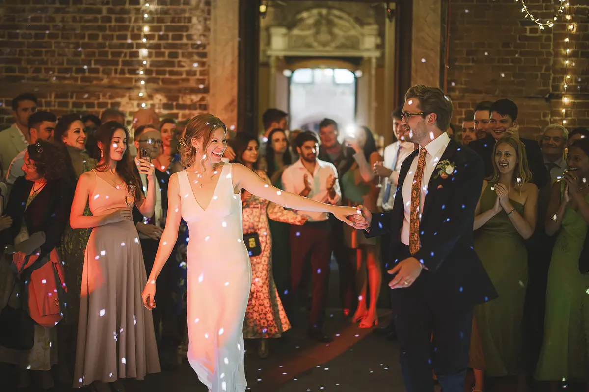 Bride and groom entering the first dance surrounded by bubbles and cheering guests at Highcliffe Castle