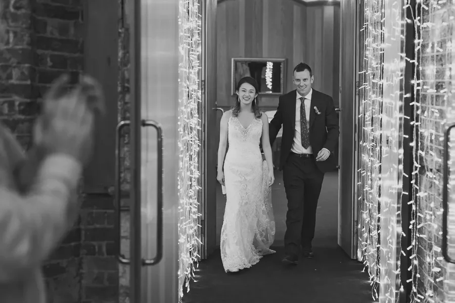 Bride and groom making their entrance into the Great Hall at Highcliffe Castle through a curtain of fairy lights