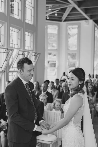 Bride and groom holding hands during their vows in the light-filled Wintergarden at Highcliffe Castle