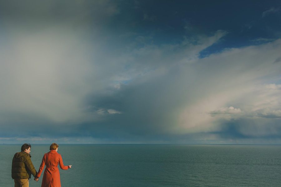 Couple holding hands on a Dorset clifftop during a coastal pre-wedding shoot