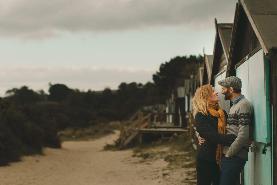 Couple embracing beside beach huts during a coastal pre-wedding shoot