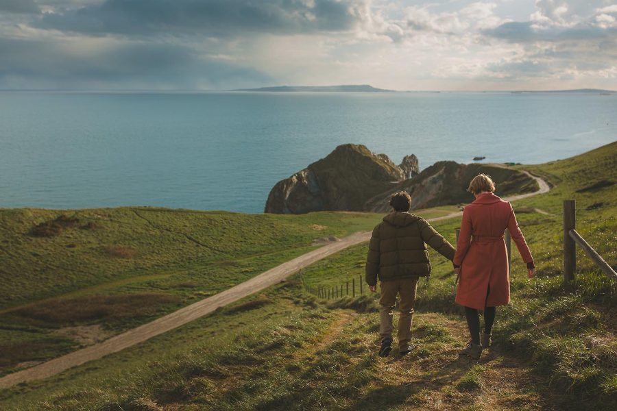 Couple walking towards Durdle Door during a pre-wedding shoot on the Dorset coast