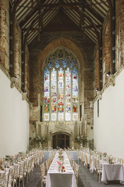 The Great Hall at Highcliffe Castle dressed for the wedding breakfast with banquet tables beneath the stained glass window