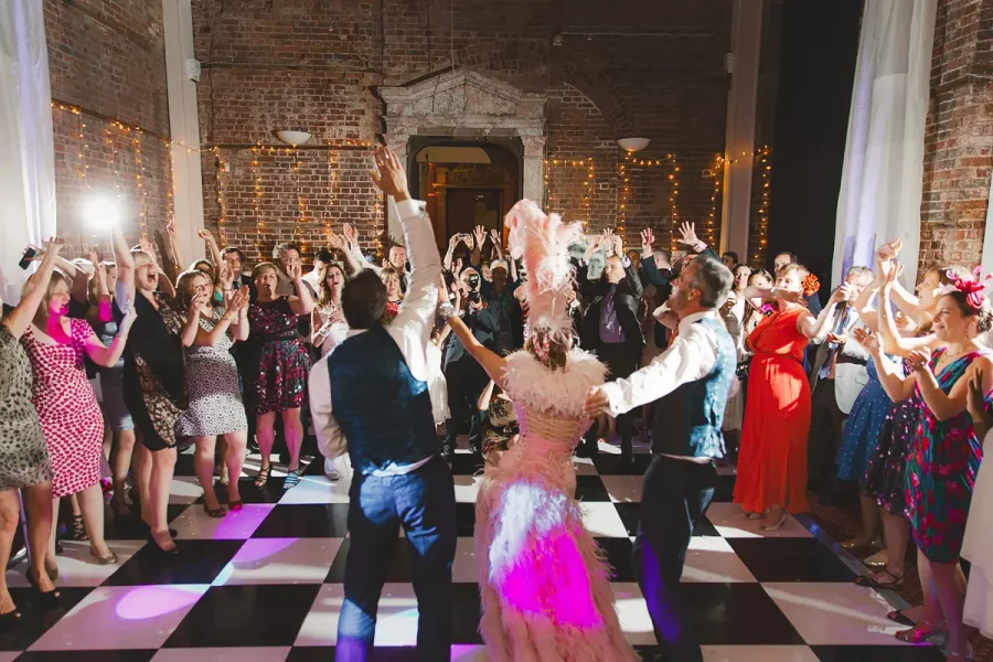 Energetic wedding reception in the Great Hall at Highcliffe Castle with a chequered dance floor and fairy lights
