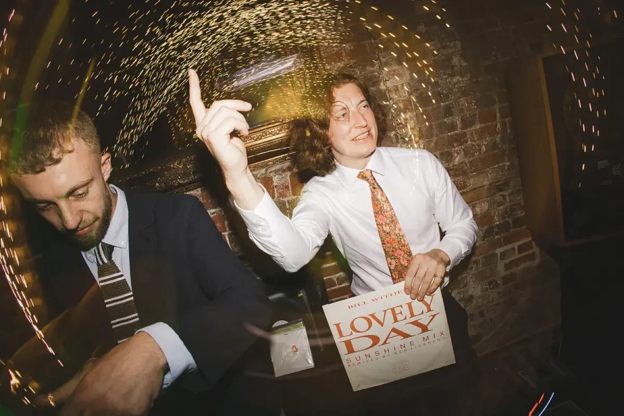 Wedding guest dancing in the Great Hall at Highcliffe Castle holding a vinyl record under a sea of fairy lights
