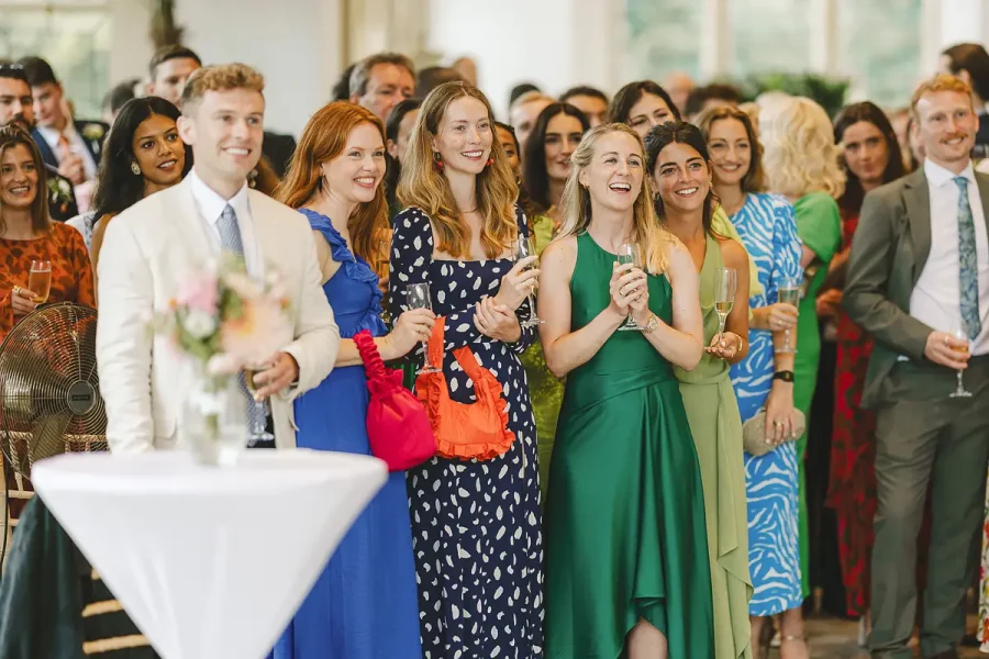 Wedding guests laughing with champagne flutes during the drinks reception in the Wintergarden at Highcliffe Castle