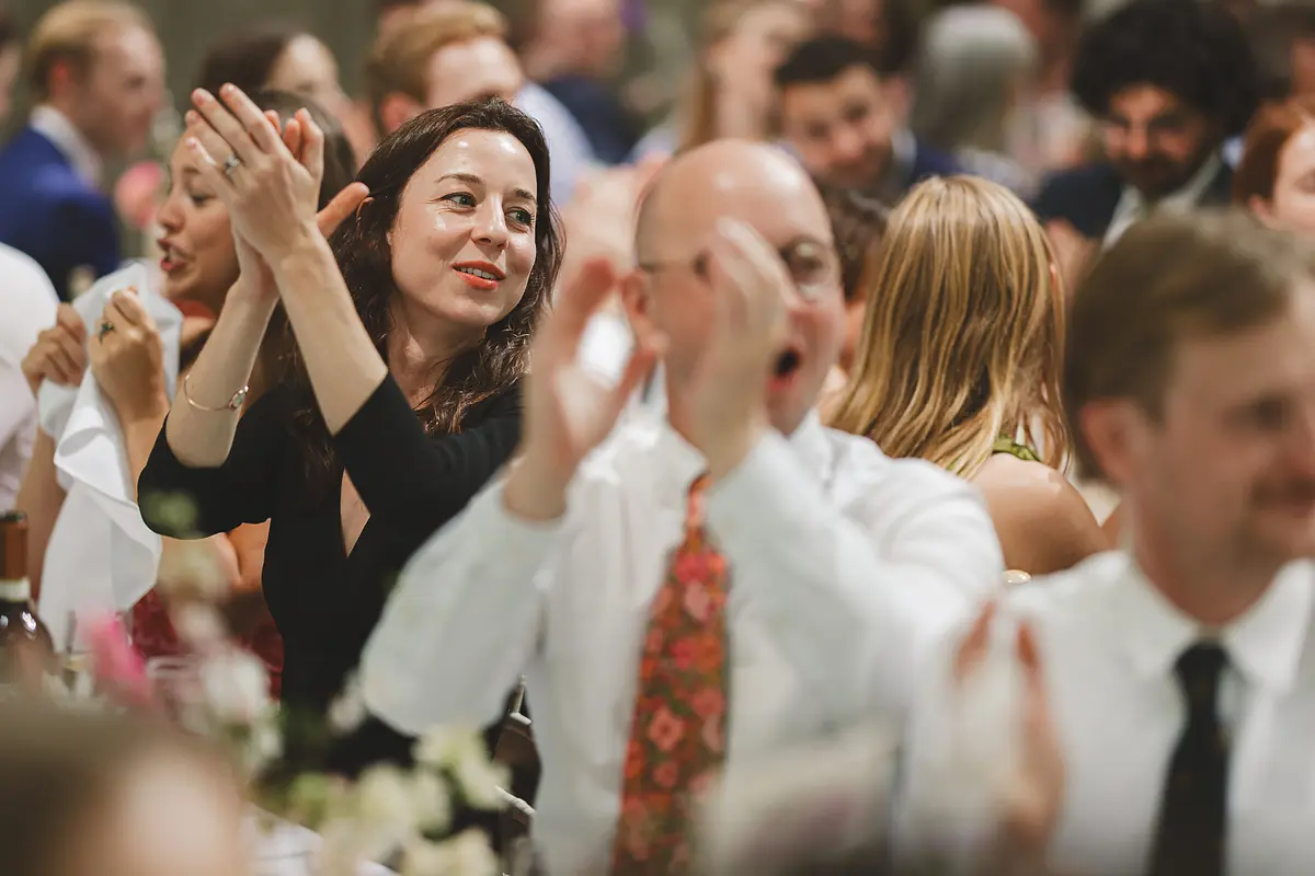 Wedding guests applauding and clapping at the wedding breakfast table in the Great Hall at Highcliffe Castle