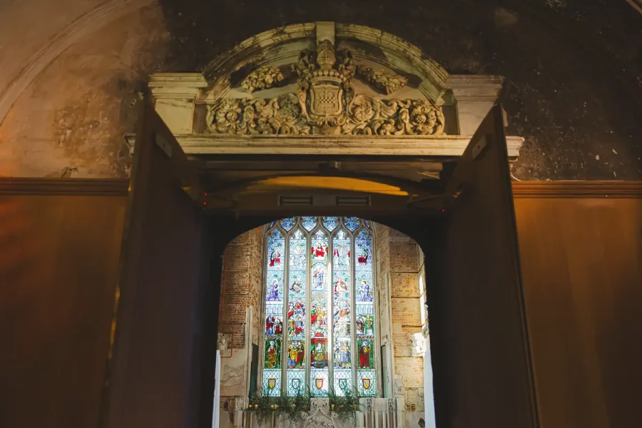 Ornate carved stone arch framing the stained glass window in the Great Hall at Highcliffe Castle