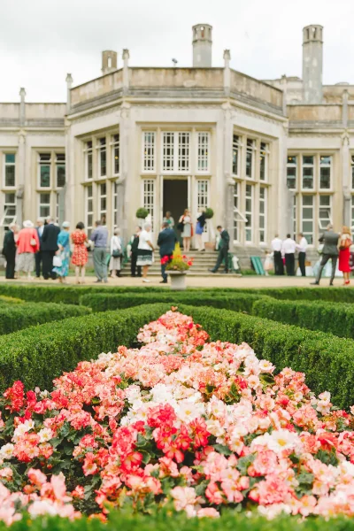 Wedding guests arriving at Highcliffe Castle with the formal parterre garden and begonias in full bloom
