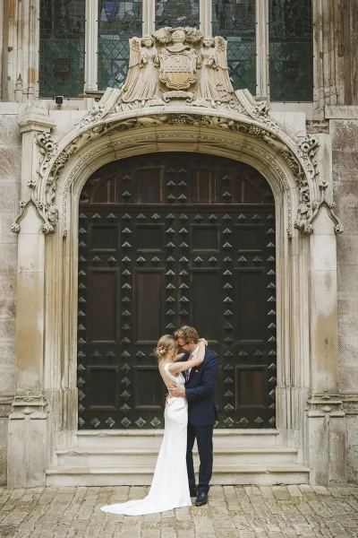 Newlyweds sharing an intimate kiss in front of the carved Gothic entrance doorway of Highcliffe Castle