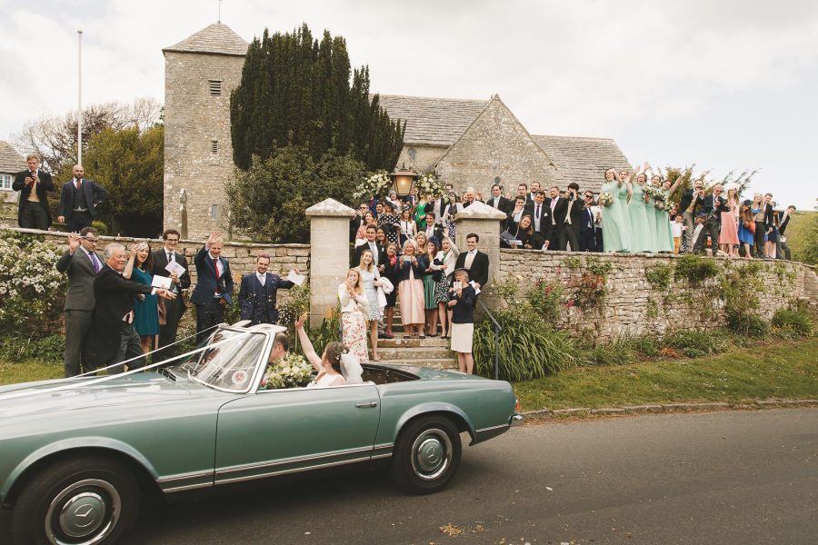Newlyweds waving from leaving the church heading back to Smedmore House wedding reception