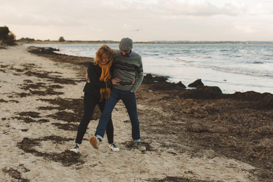 Relaxed couple walking along the shoreline during a pre-wedding shoot