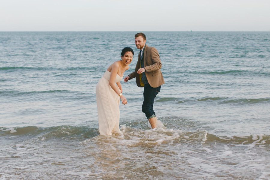 Couple laughing in the sea during a Sandbanks pre-wedding shoot in Dorset