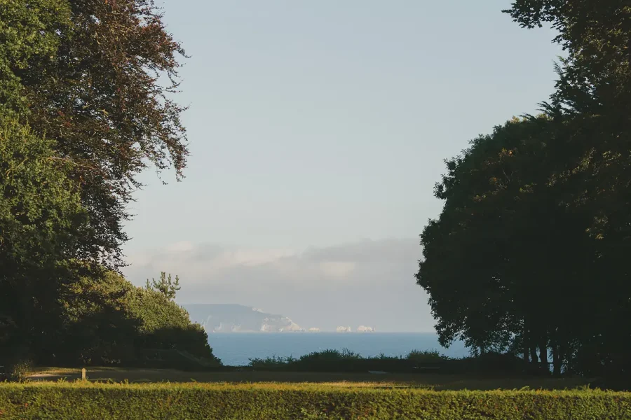 View through the trees across the Highcliffe Castle grounds towards the sea and distant white cliffs