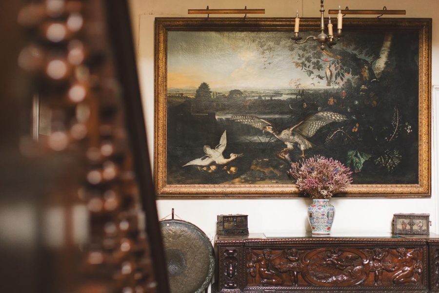 Ornate antique oil painting of waterfowl hanging above a carved wooden sideboard in the interior of Smedmore House