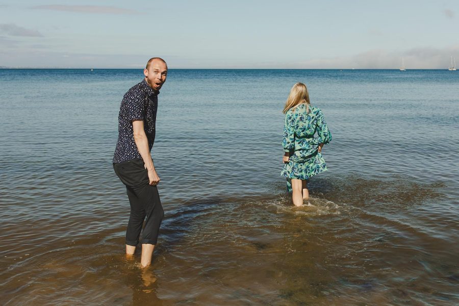 Couple walking into the sea during a relaxed pre-wedding shoot at Studland Bay in Dorset