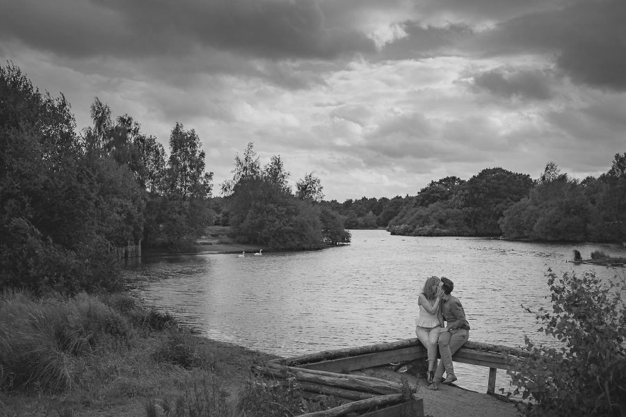 Black and white portrait of couple sitting together by the water’s edge