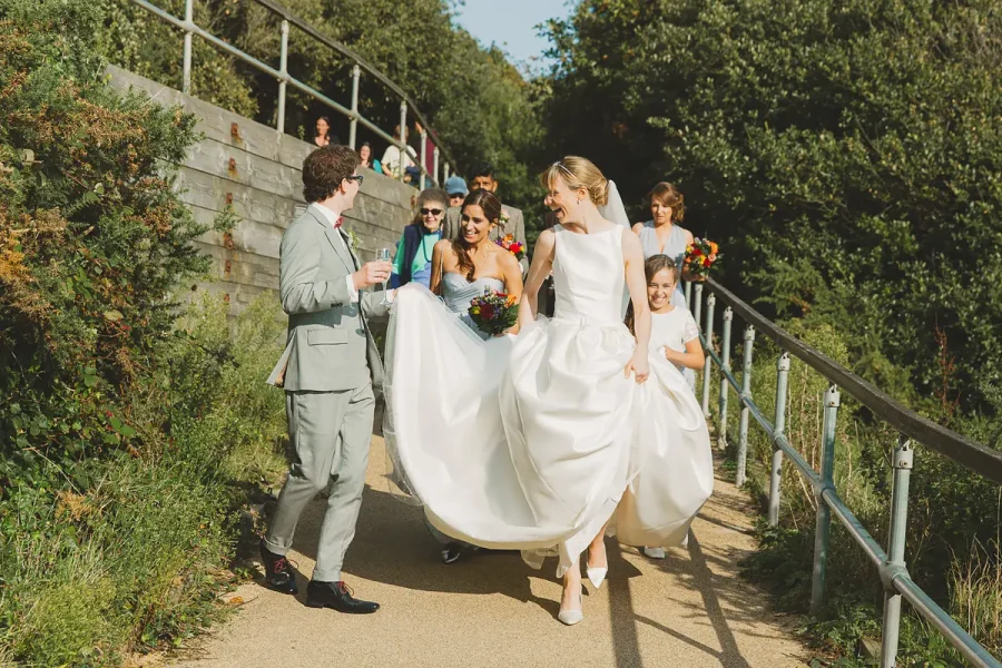 Bridal party walking down a tree-lined coastal path near Highcliffe Castle on a bright sunny day