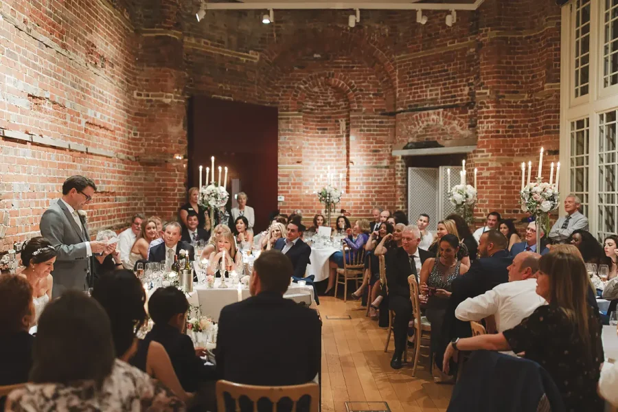 Wide view of the Highcliffe Castle Great Hall set for the wedding reception with tall floral centrepieces