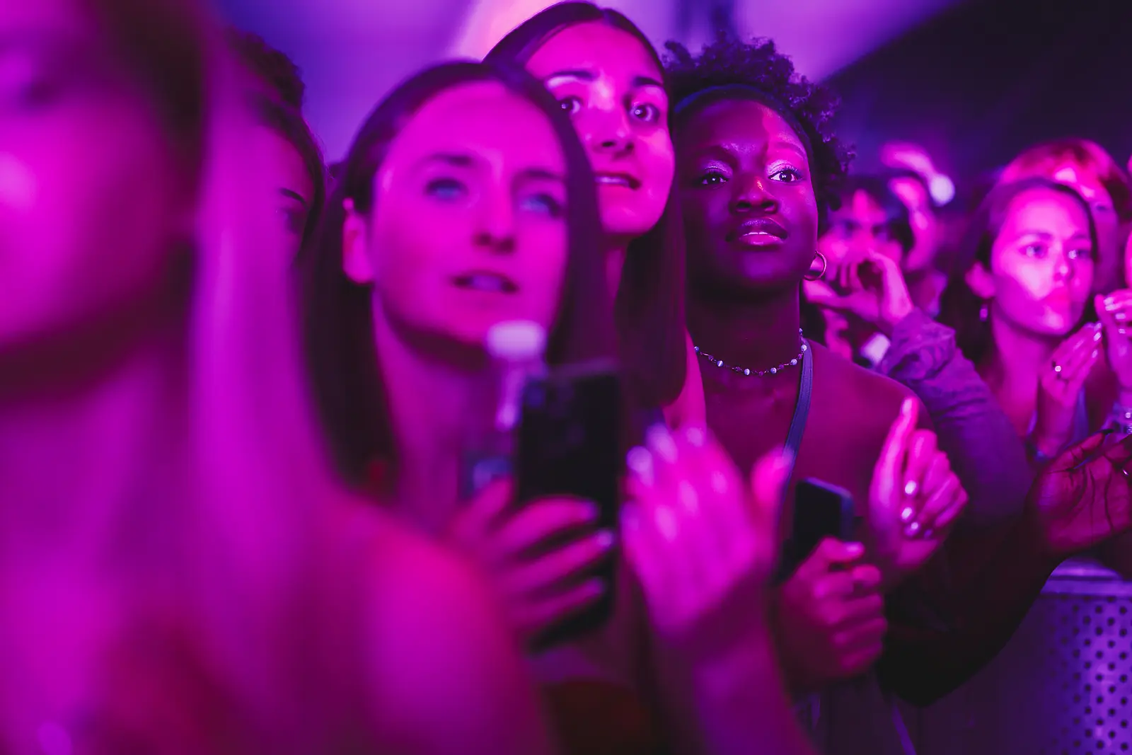 Crowd members absorbed in the performance under deep magenta stage lighting at a summer ball concert