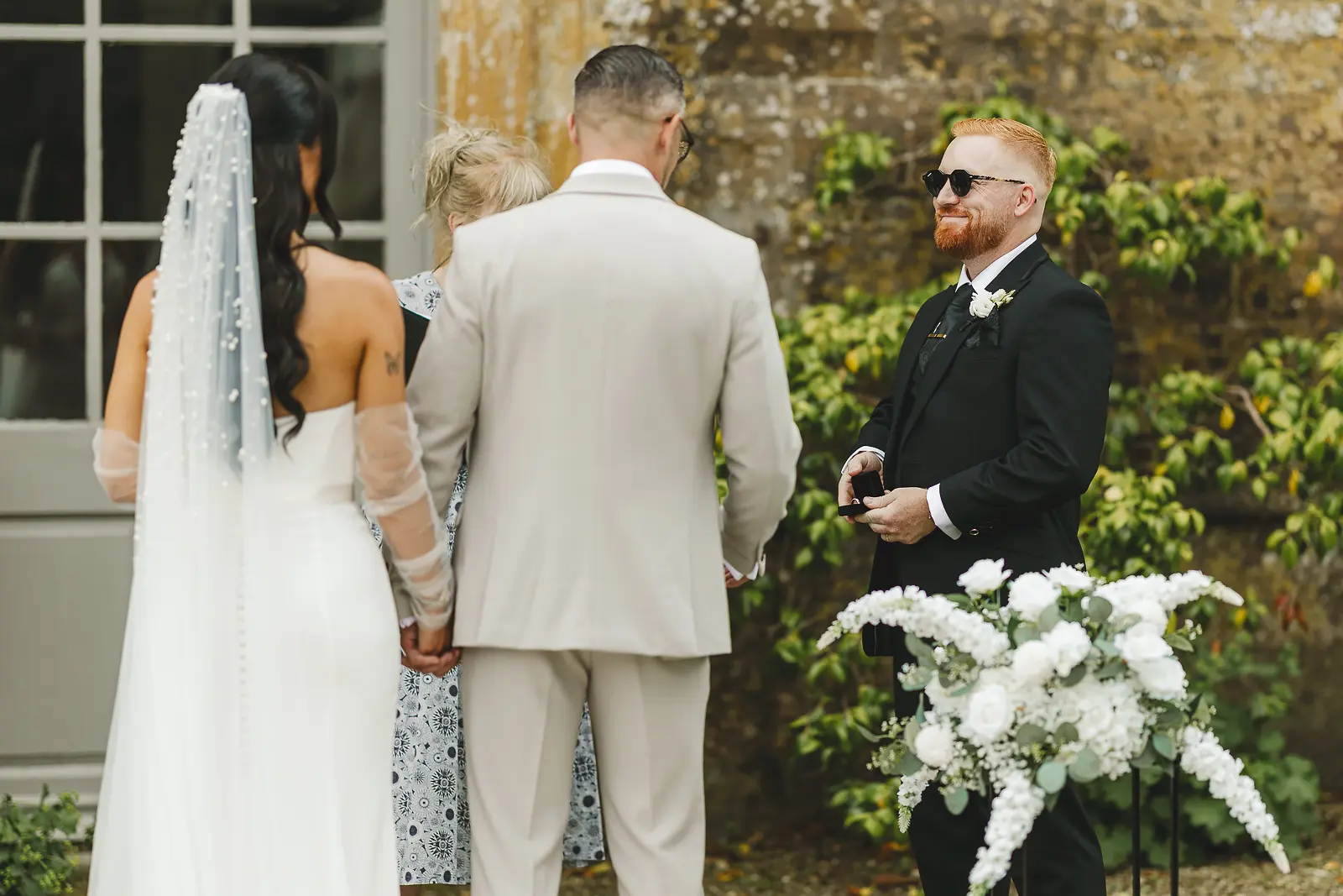 Best man holding open the ring box with wedding rings ready during the outdoor ceremony at Mapperton House