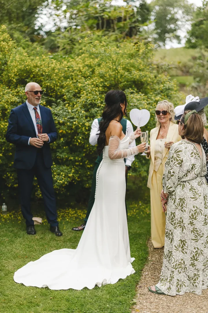 Bride chatting and laughing with guests during the outdoor drinks reception in the Mapperton Gardens, relaxed and joyful