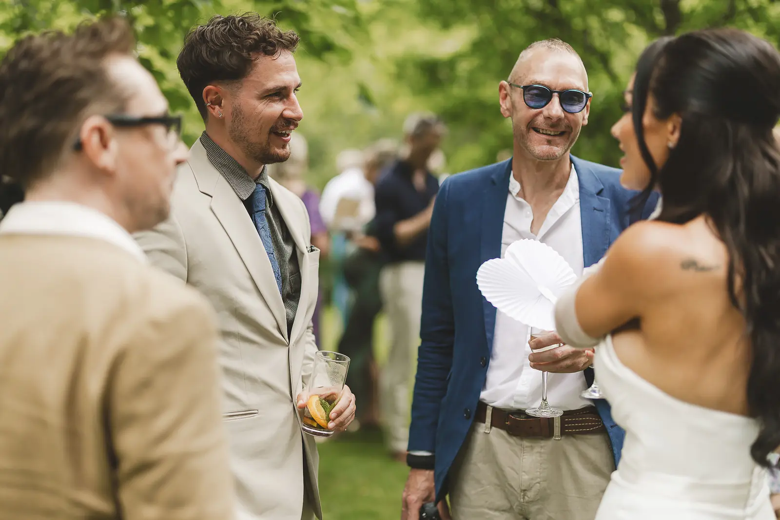 Bride laughing with guests during the outdoor drinks reception at Mapperton, a candid joyful moment in the summer garden