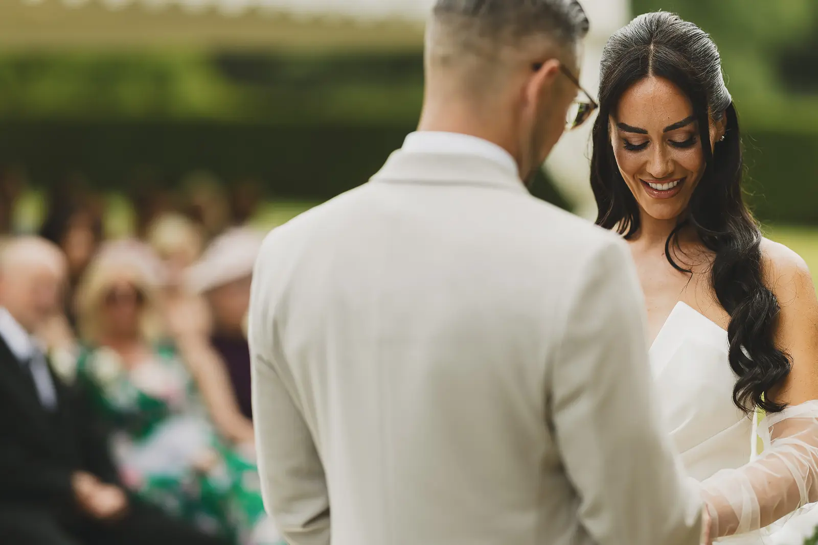 Bride smiling joyfully during the outdoor ceremony vows at Mapperton House, natural light and lush garden behind