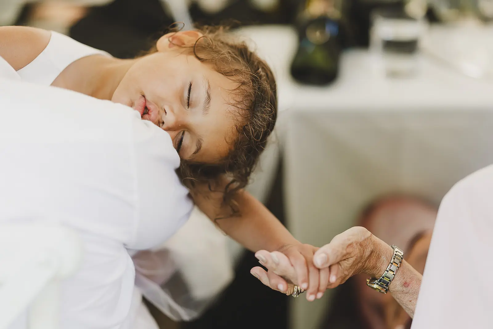 Candid moment of a child holding hands with an elderly guest at the wedding reception, a sweet intergenerational connection