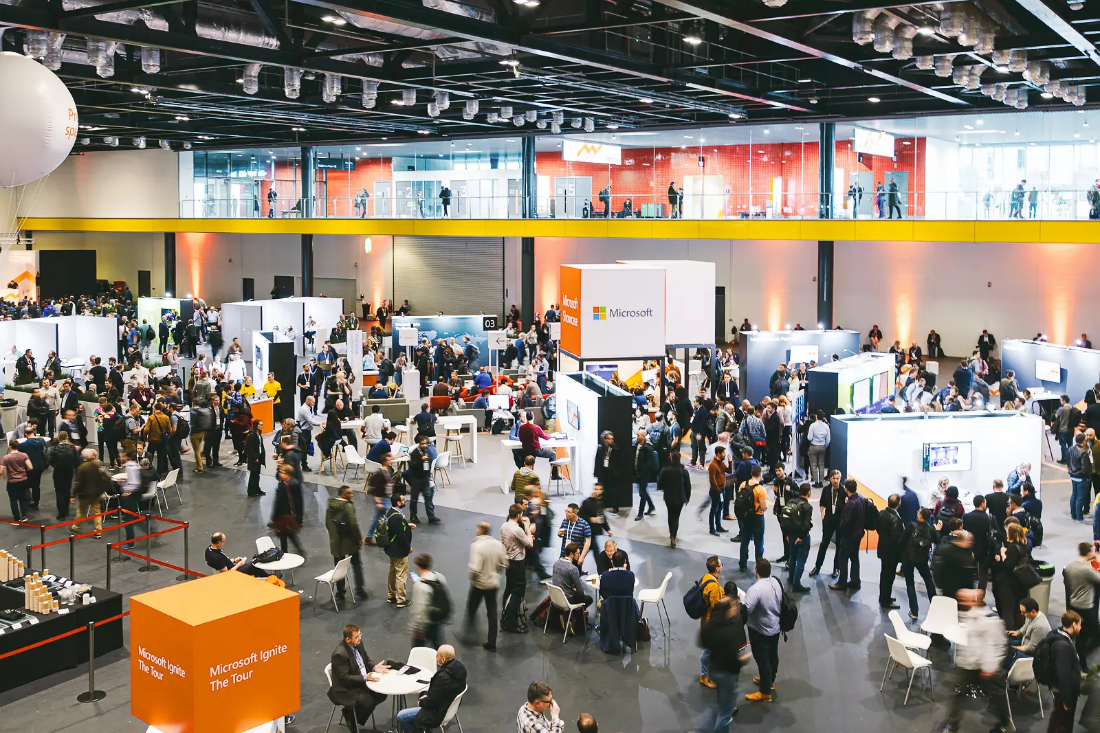 Large conference exhibition hall with delegates, sponsor stands and networking activity at a business event