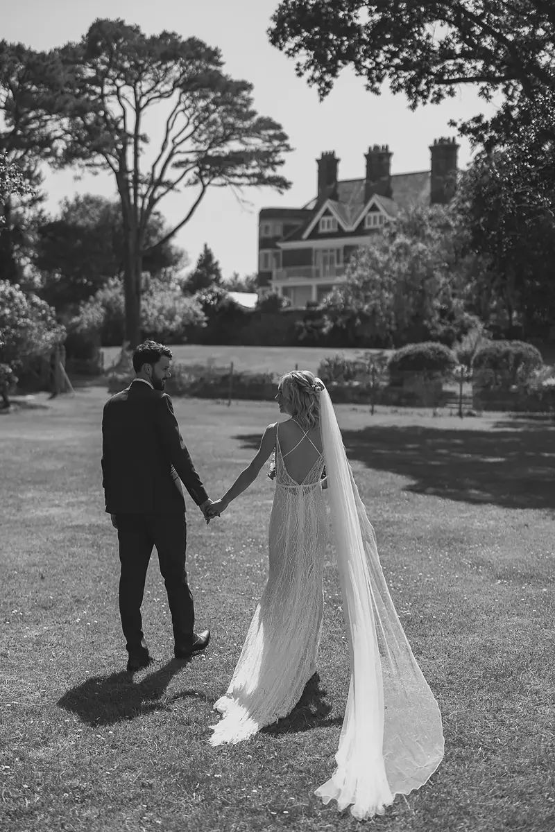 Bride and groom walking hand in hand across the lawn at a Dorset wedding venue