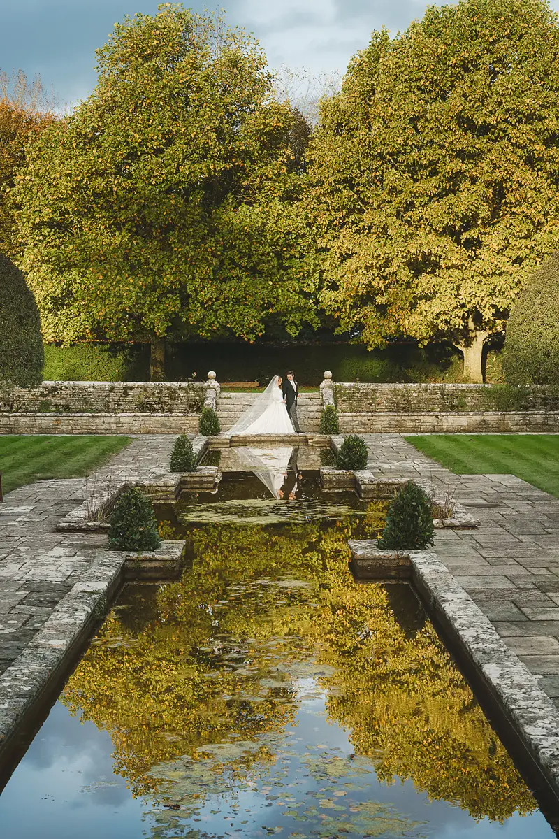 Bride and groom portrait reflected in a long garden pool at a Dorset wedding venue