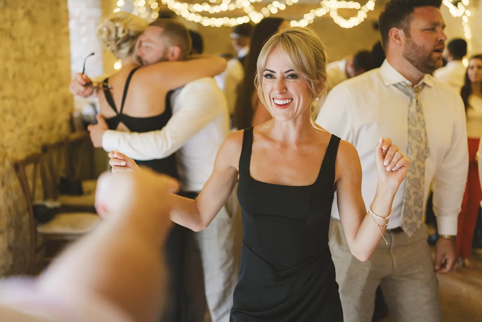 Guest dancing and celebrating at the evening reception in the stone barn, fairy lights creating a warm glowing atmosphere