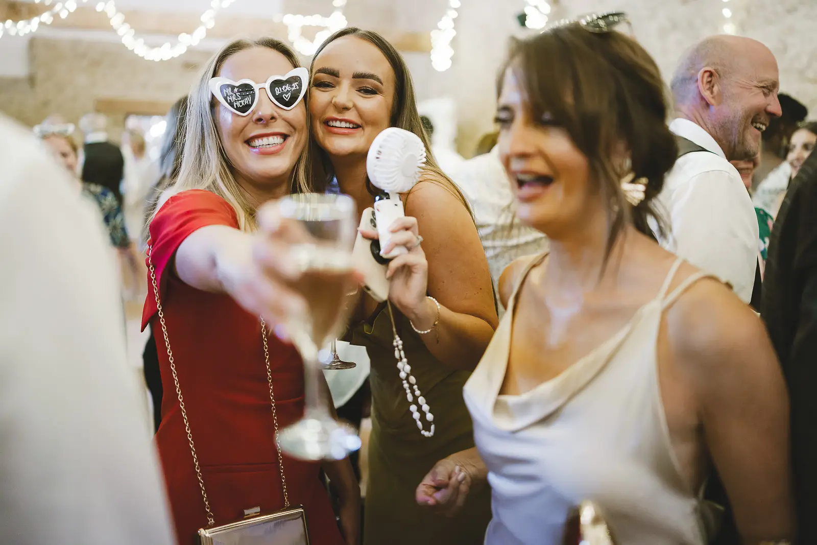 Wedding guests celebrating at the evening reception wearing novelty glasses, laughter and fun on the dance floor