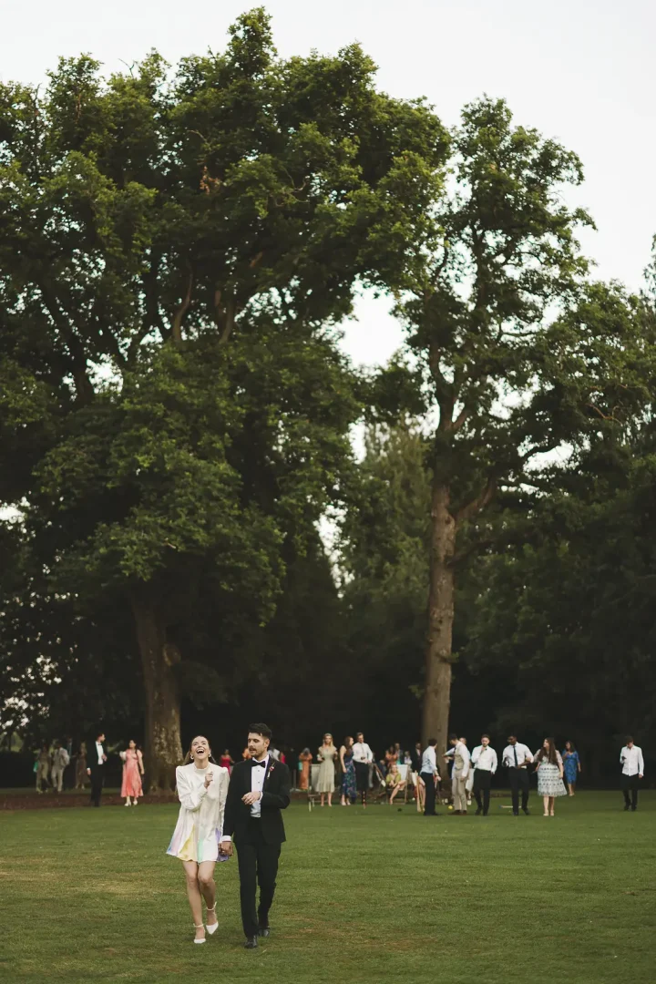 Bride and groom walking through evening drinks reception at Larmer Tree Gardens wedding