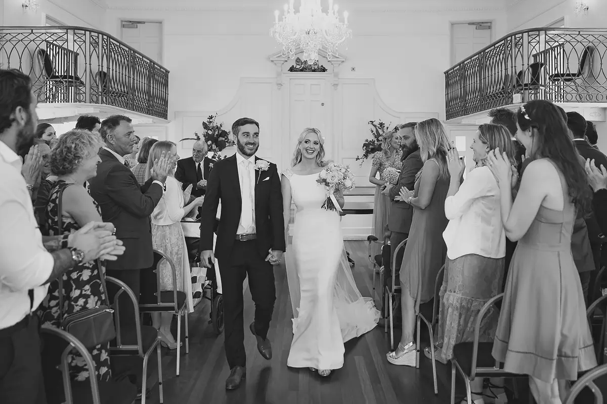 Bride and groom walking down the aisle after their ceremony at Poole Guildhall Register Office surrounded by guests