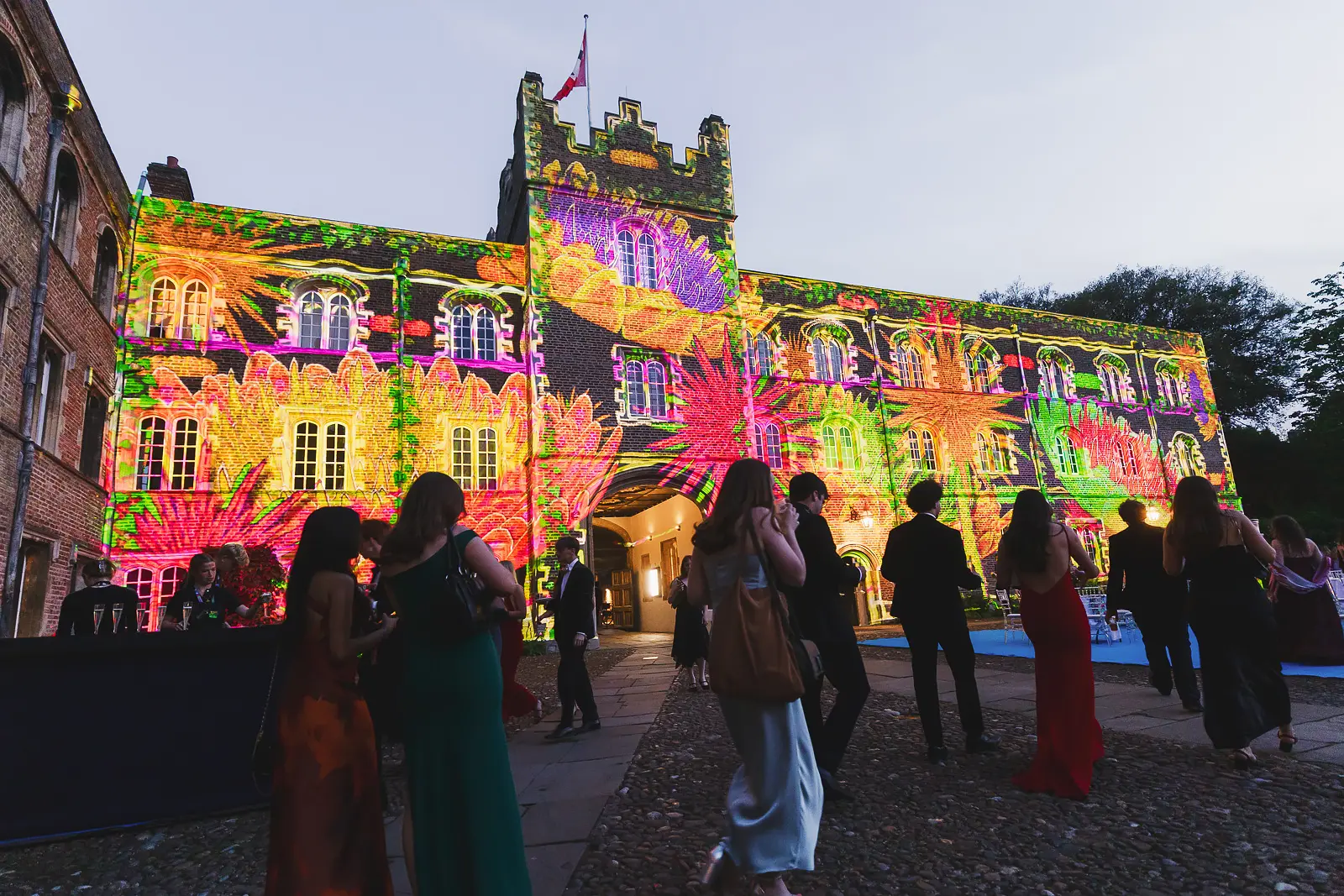 Psychedelic botanical projection mapping covering the Gothic college facade at a Cambridge May Ball