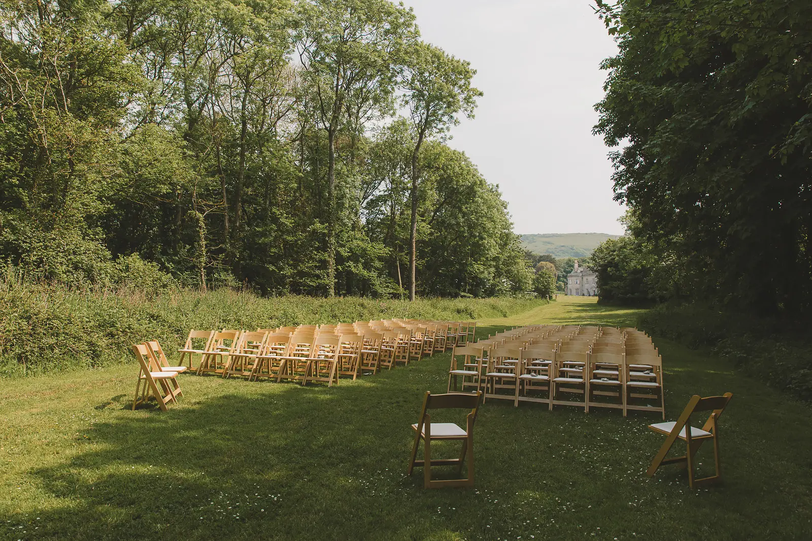 Outdoor wedding ceremony chairs set along the tree lined lawn at Smedmore House in Dorset