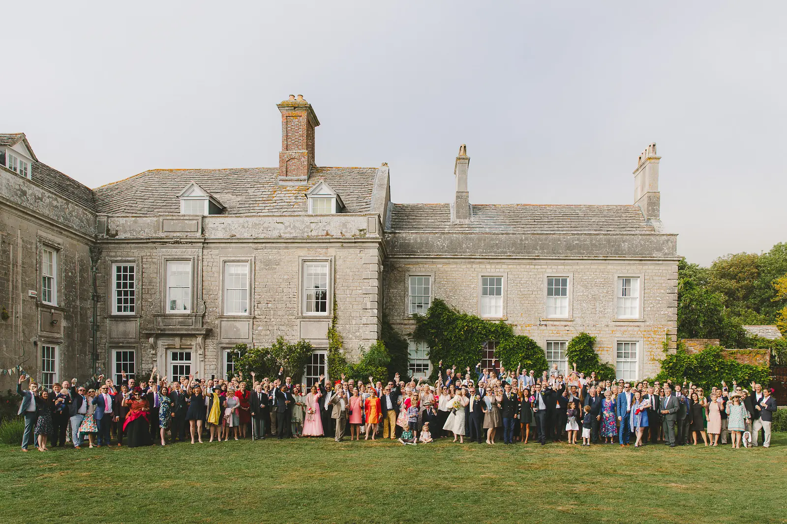 Large wedding group photo on the lawn in front of Smedmore House in Dorset