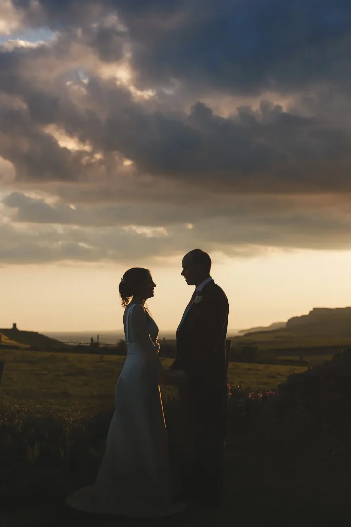 Bride and groom silhouetted at sunset overlooking Kimmeridge Bay near Smedmore House in Dorset