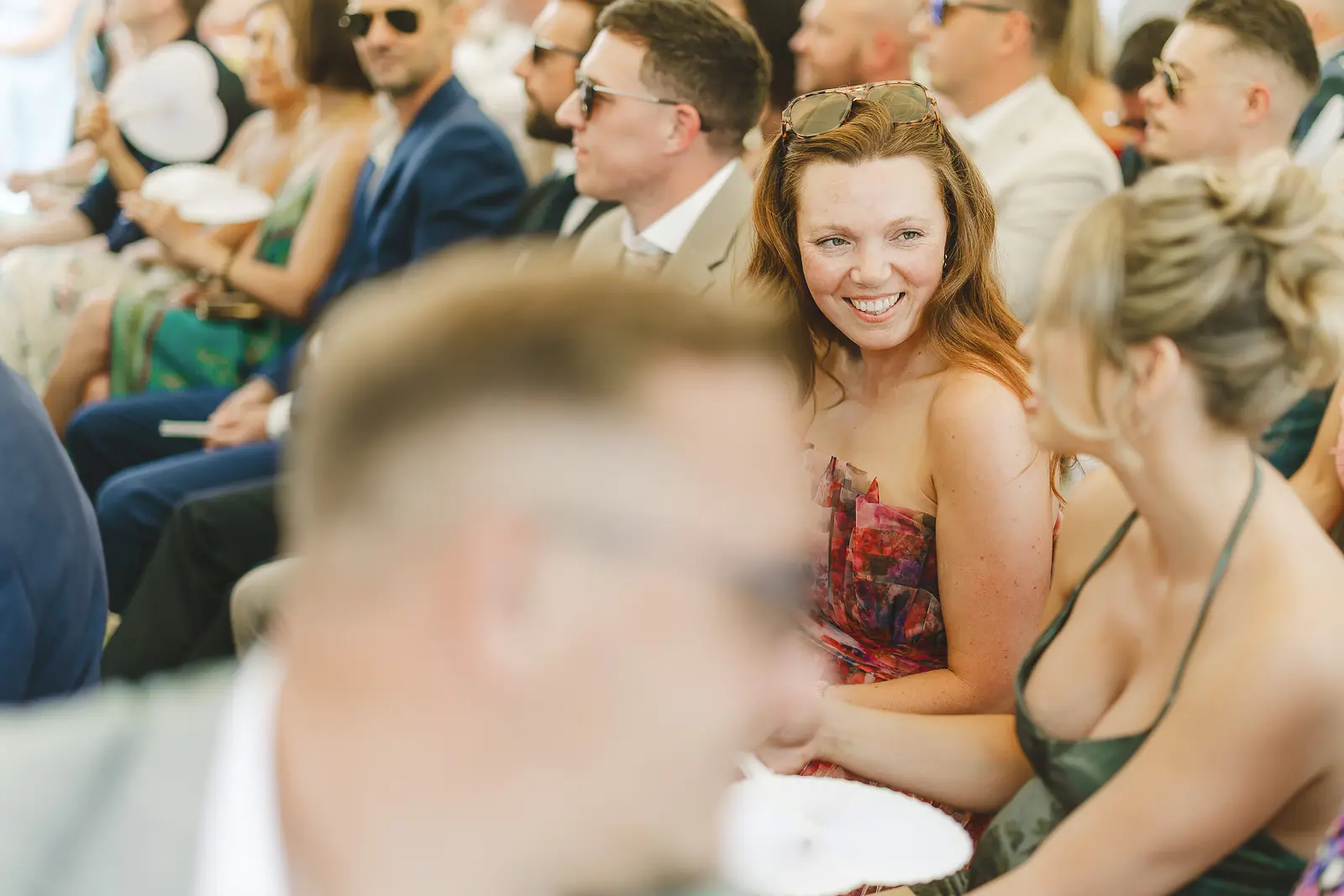 Smiling guest seated in the marquee waiting for the ceremony to begin, warm summer light