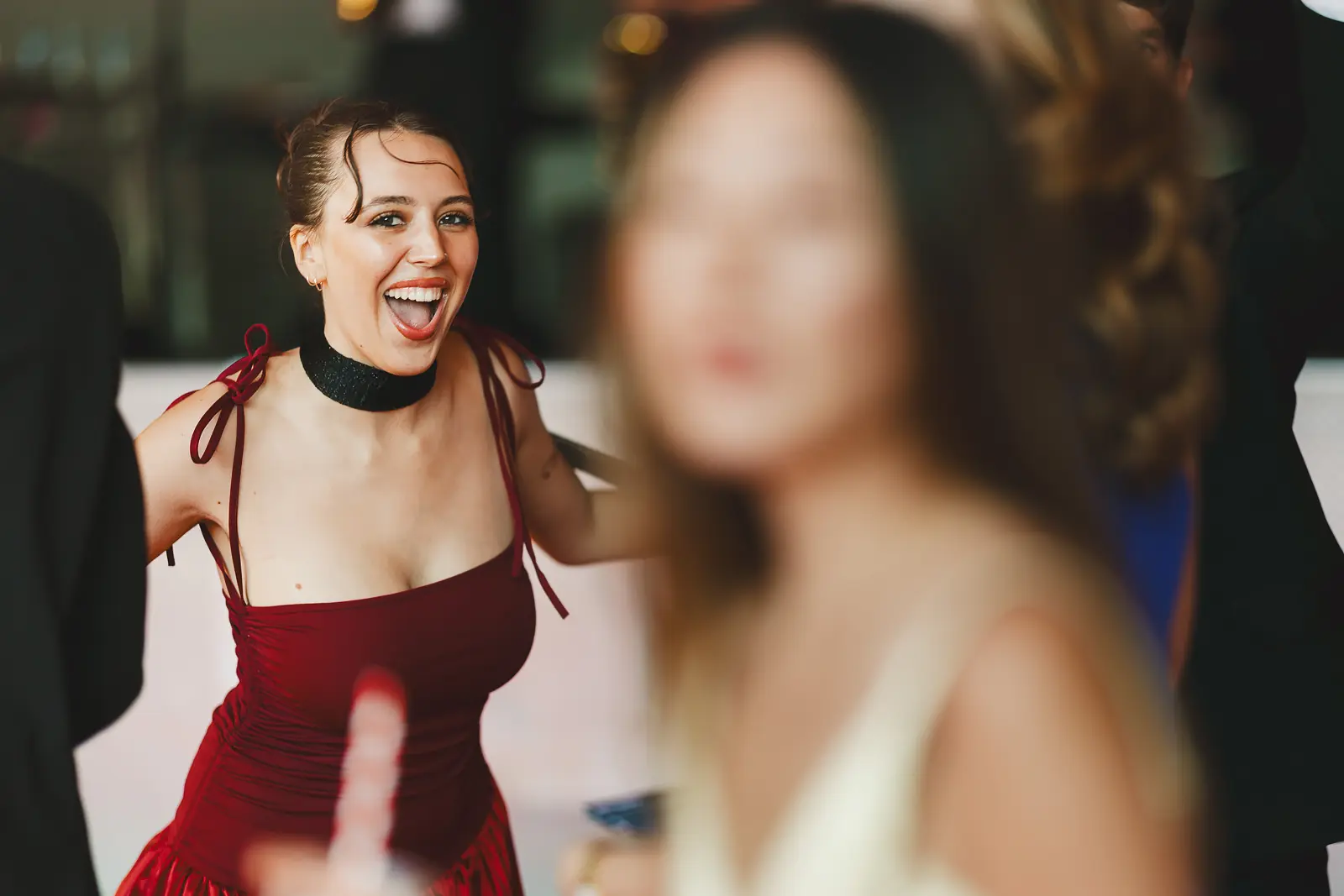 Spontaneous candid moment of a guest in a burgundy dress laughing during a summer ball event
