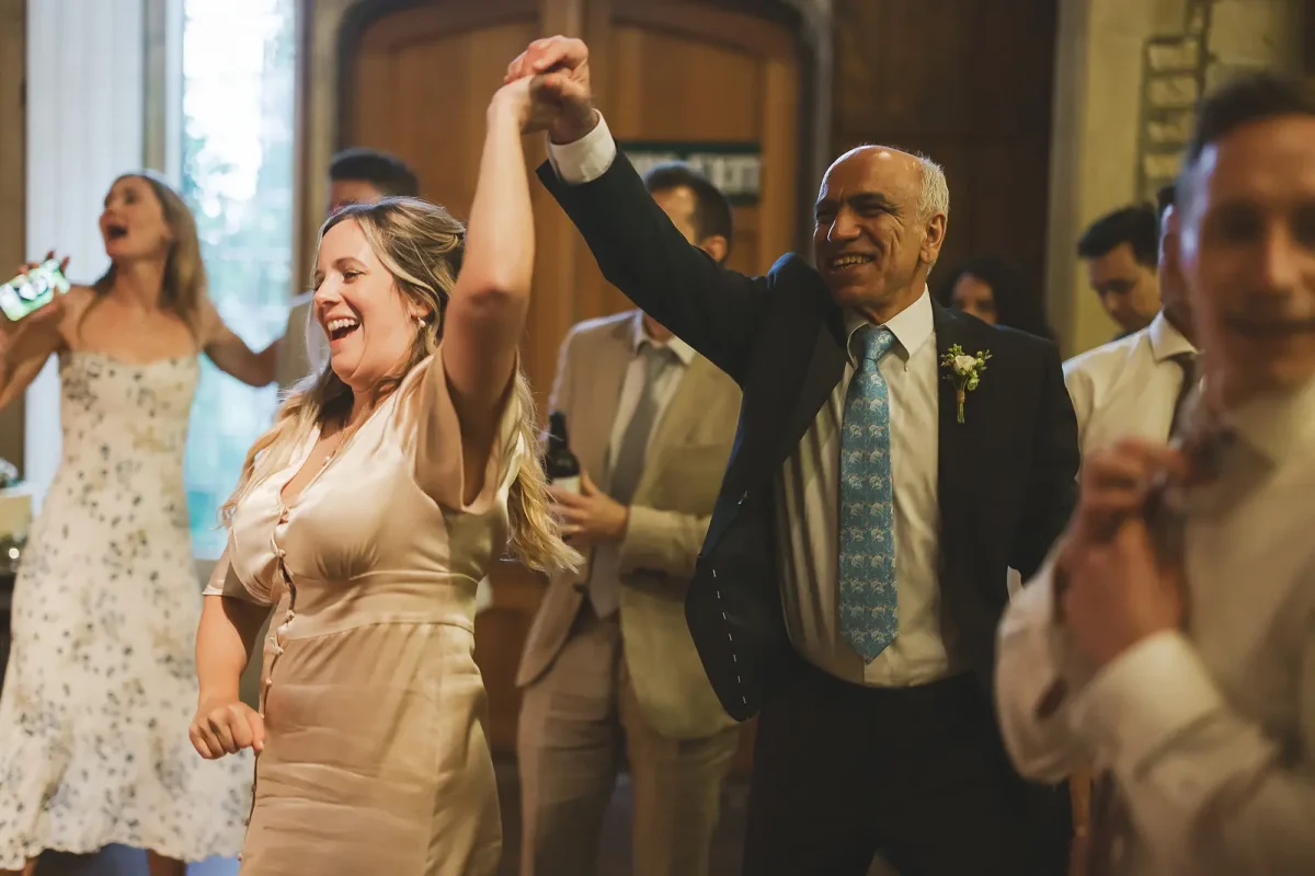 Wedding guests of all ages laughing and dancing together at the evening reception in the tithe barn at Hinton St Mary Estate Dorset