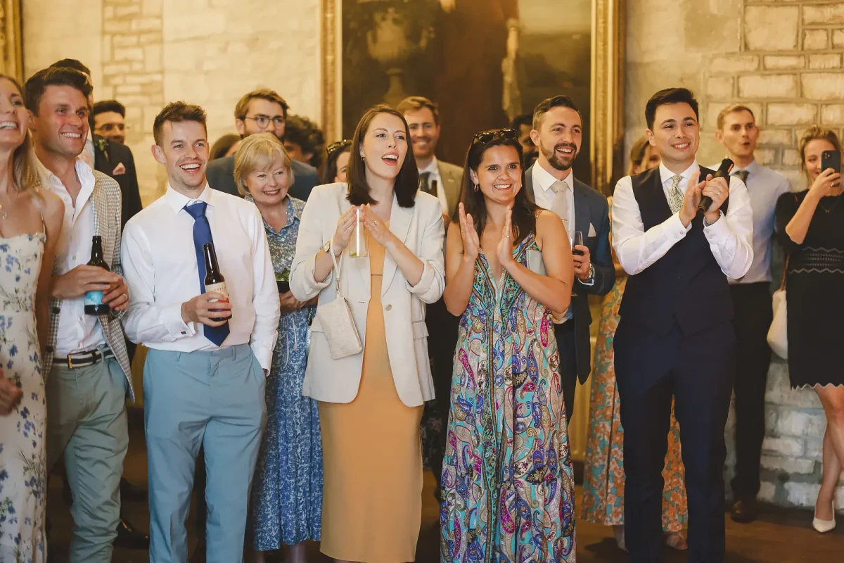 Wedding guests cheering and clapping as they watch the first dance in the warm tithe barn at Hinton St Mary Estate Dorset